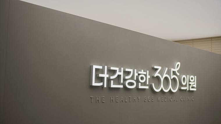 회색 벽면에 '더건강한 365의원'이라는 한글과 영문이 적힌 입체적인 간판이 부착되어 있다