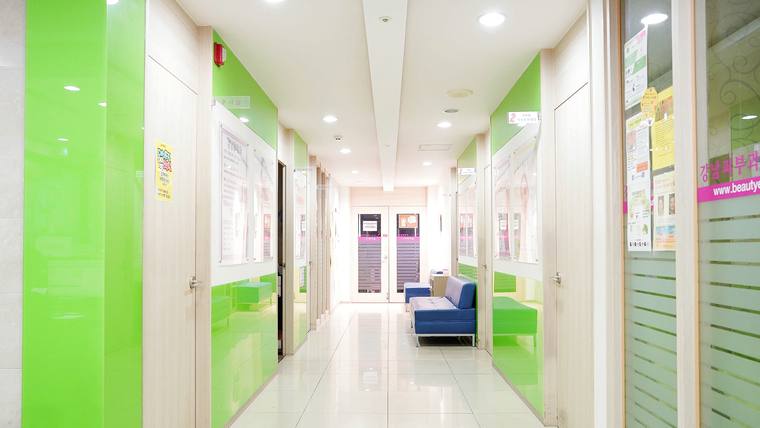 강남피부과의원 — 연한 녹색과 흰색이 조화된 현대적인 병원 복도와 대기 공간의 모습