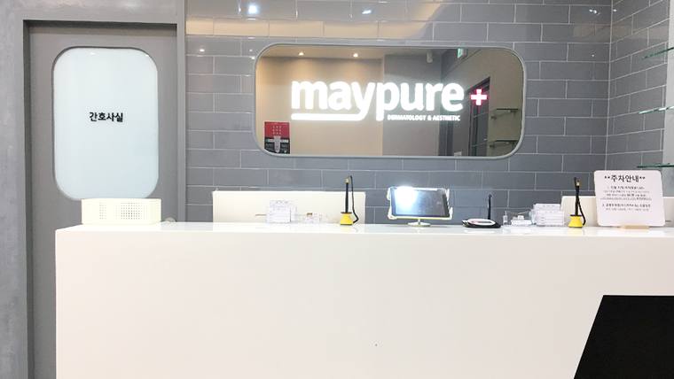 메이퓨어의원 — 흰색 접수대와 'maypure+' 로고가 적힌 벽면이 있는 병원 내부의 안내 데스크 모습