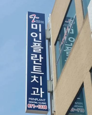 미인플란트치과의원 — 파란색 바탕에 흰색 글씨로 '미애플란트치과'라고 적힌 병원 간판이 건물 외벽에 설치되어 있다