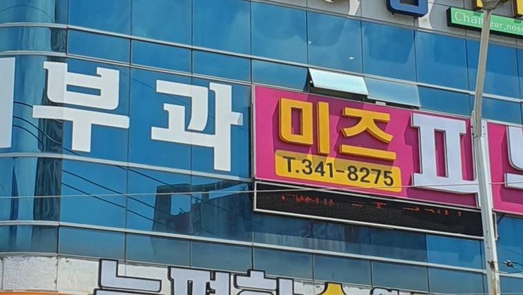 미즈피부과의원 — 건물 외벽에 파란색과 분홍색 바탕의 한글과 전화번호가 적힌 간판이 설치되어 있다