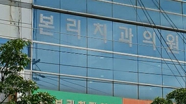 본리치과의원 — 건물 외벽에 '분리치과외원'이라는 한글 문구가 적힌 파란색 유리창이 보입니다