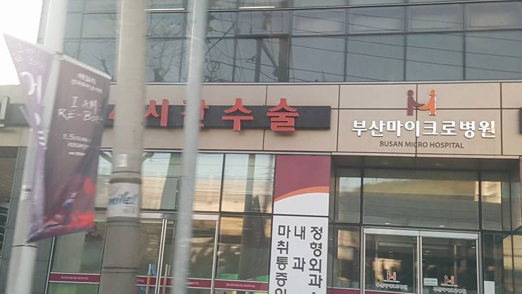 부산마이크로병원이라는 문구와 진료 과목이 적힌 간판이 있는 병원 입구의 모습
