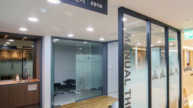 서울나솔마취통증의학과의원 — 병원의 운동치료실 입구와 안내 데스크가 보이는 내부 복도 공간이다