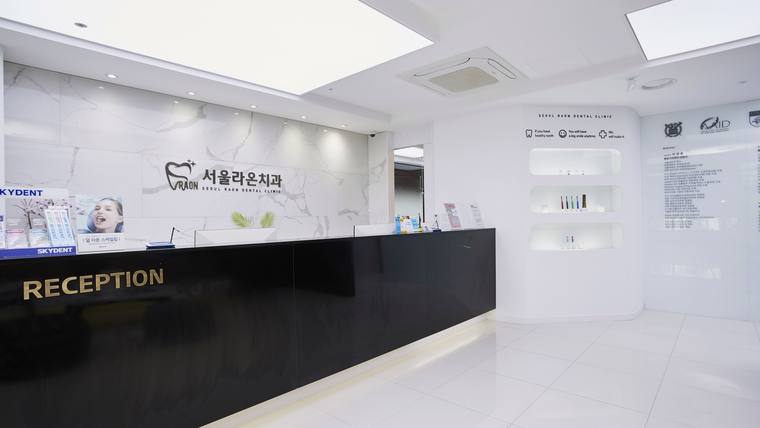 서울라온치과의원 — 흰색 벽면과 검은색 접수대가 있는 병원 로비의 내부 모습