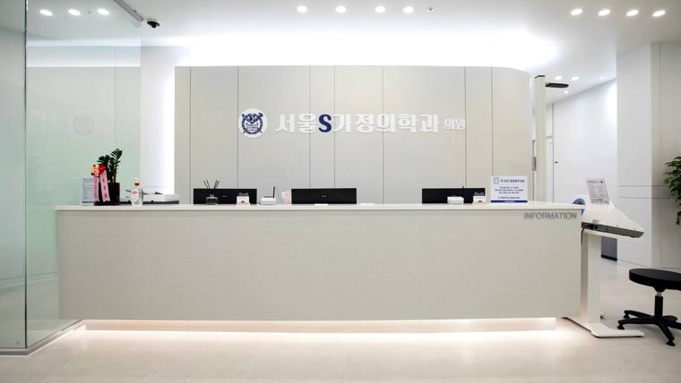 서울에스S가정의학과의원 — 흰색 벽면과 긴 안내 데스크가 있는 병원의 접수처 내부 모습