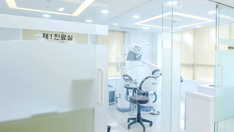 석플란트치과병원 — 유리문과 진료용 의자, 의료 장비가 배치된 병원 내부 진료실의 모습