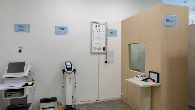 신세계외과의원 — 병원 접수대와 대기 공간에 안내 표지판과 키오스크, 번호표 발행기 등이 배치되어 있는 실내 모습