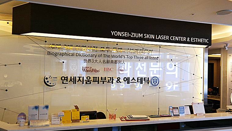 피부과 병원의 접수대 위에 '연세지움피부과 & 에스테틱'이라는 문구가 적힌 간판과 홍보물이 배치되어 있다