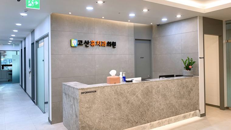 고산휴치과의원 — 대리석 느낌의 질감으로 마감된 접수대와 '종합검진센터'라는 문구가 적힌 벽면이 보이는 병원 로비의 모습
