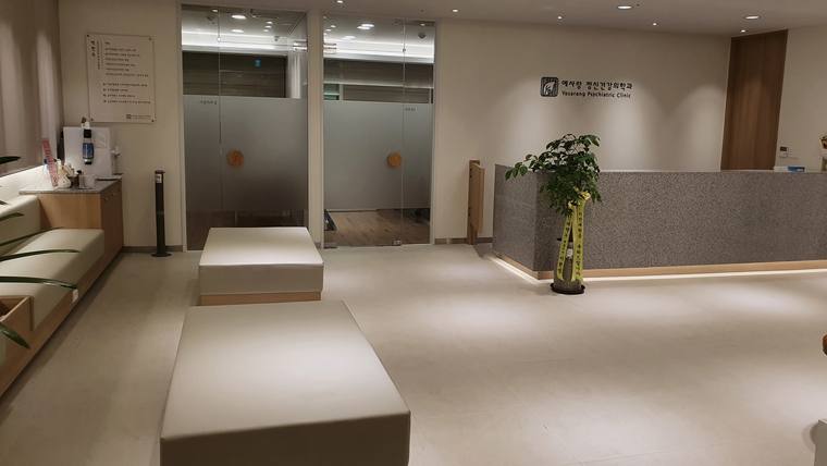 예사랑정신건강의학과의원 — 병원의 대기실 내부에 접수대, 대기용 의자, 안내 표지판, 그리고 두 개의 문이 있는 공간이 보입니다