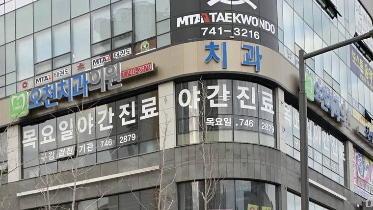 오천치과의원 — 치과 병원 건물의 외벽에 '치과'와 '목요일 야간진료'라는 문구가 적힌 간판들이 설치되어 있다