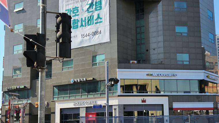 이삭신경과의원 — 건물 외벽에 병원 간판과 카페가 위치해 있으며 전방에 신호등이 있는 거리 풍경