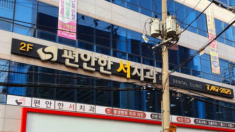 건물 외벽에 '편안한 치과'라는 문구가 적힌 커다란 간판이 설치되어 있다