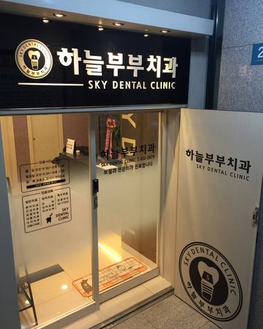 하늘부부치과의원 — 치과 병원 입구에 설치된 간판과 유리문이 보이는 사진