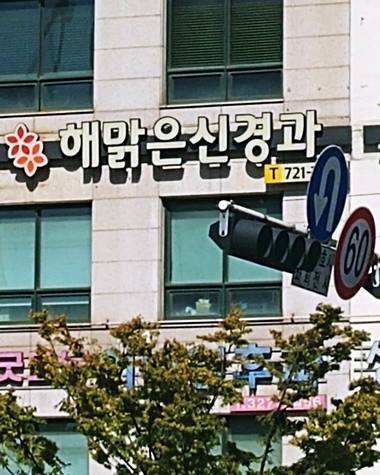 병원 건물 외벽에 '해맑은신경과'라는 문구와 로고가 포함된 간판이 설치되어 있다