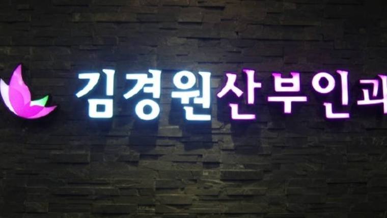 어두운 벽면을 배경으로 분홍색 꽃 모양 로고와 김경원산부인과라는 한글 문구가 적힌 조명 간판
